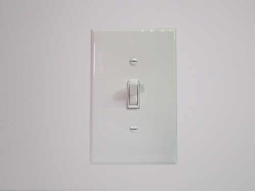 Front view of a traditional American light switch. A lever is sticking out from the front, used to toggle the lights on and off.