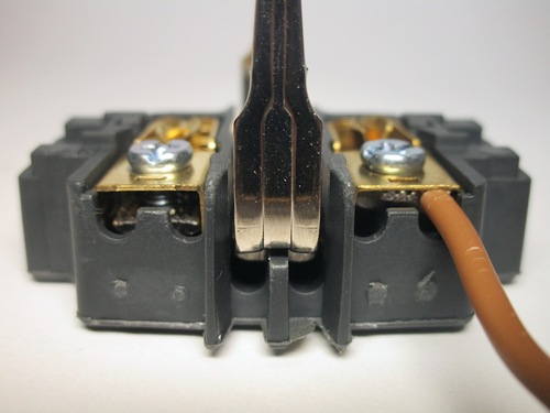 Wire terminals on a European socket using screws. The screw pushes on a clamp which holds the wire.