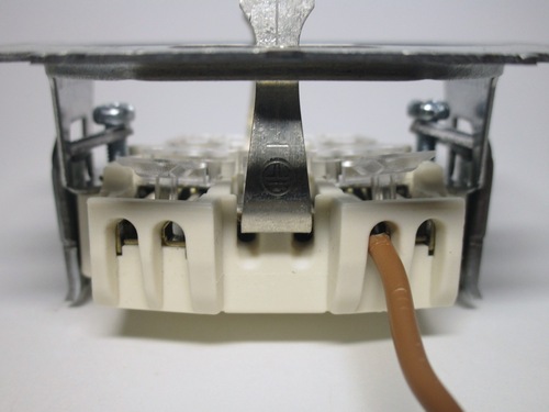 Push-in terminals on a European socket. The wire is held with an internal spring. A lever is used to remove the wire.