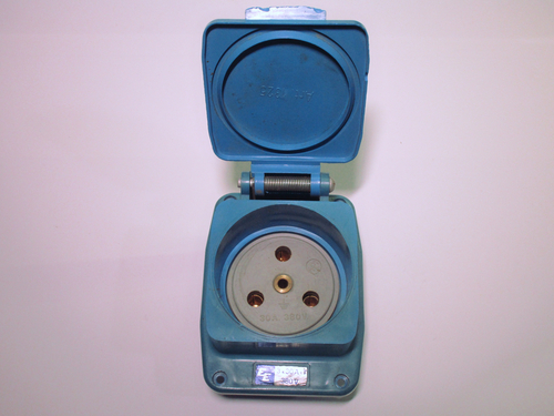 View of the power socket with the lid open. There are four holes, three for the phases and a central one for the earth.