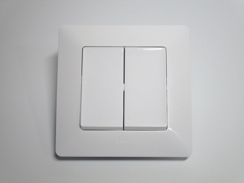 Front view of the switch. It's made of white plastic with a modern flat look. The surface is divided in half for the two switches.