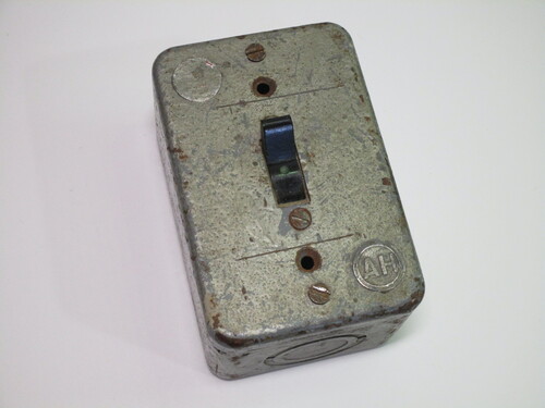 Front view of the switch. The case is made of metal, with the lever of the switch sticking out.