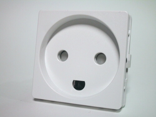 Front view of the Danish power socket. The socket has two holes for the line and neutral pins, protected by shutters, and a semi-circular hole for the earth. A small recess is present.