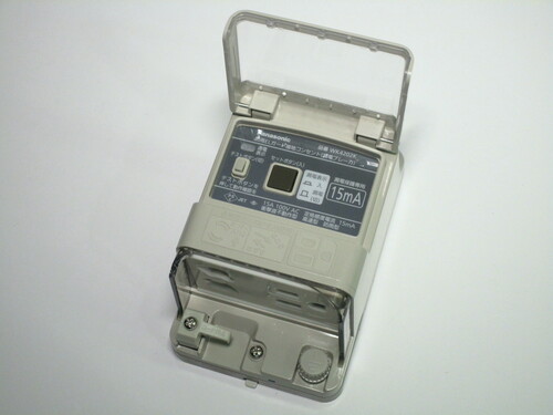 The device with its front lid open. Two buttons are present, test and reset.