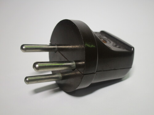 Front view of the Felms plug. It's made of brown bakelite and has three round pins.