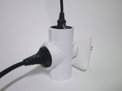 Adaptor plugged into a socket, with two plugs connected to it.