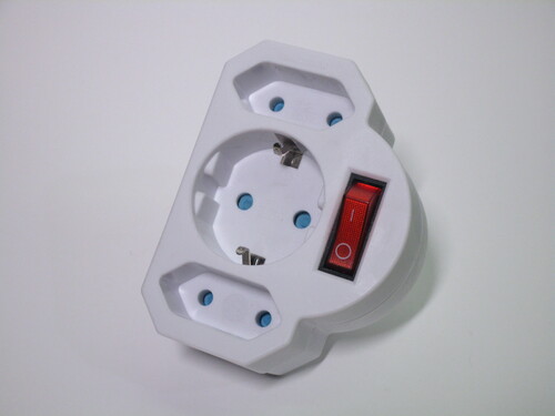 Front of the adaptor. It has a Schuko socket in the middle and two Europlug sockets on the top and bottom of it, as well as a switch on the right.