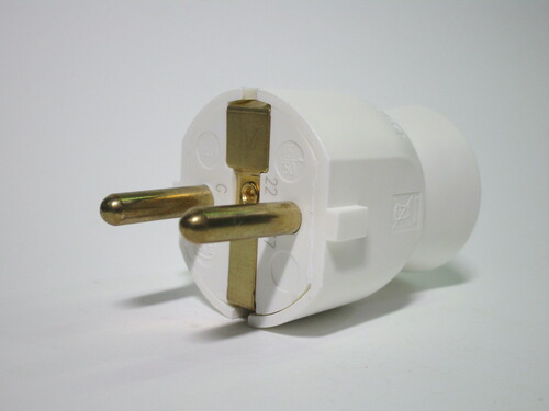 Front view of the plug. It's made of white plastic with brass-coloured pins.