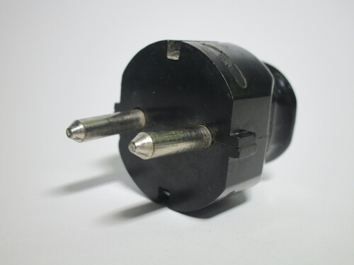 Side view of the plug. It's made of brown bakelite and has pointy pins.