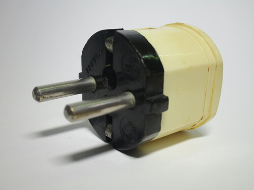 Front view of the plug. It's made out of a creamy beige bakelite, with a brown piece on the front where the pins are.