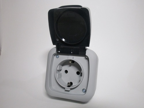 Front view of the socket, with the lid open. The socket is made of light grey plastic, with a dark grey lid.