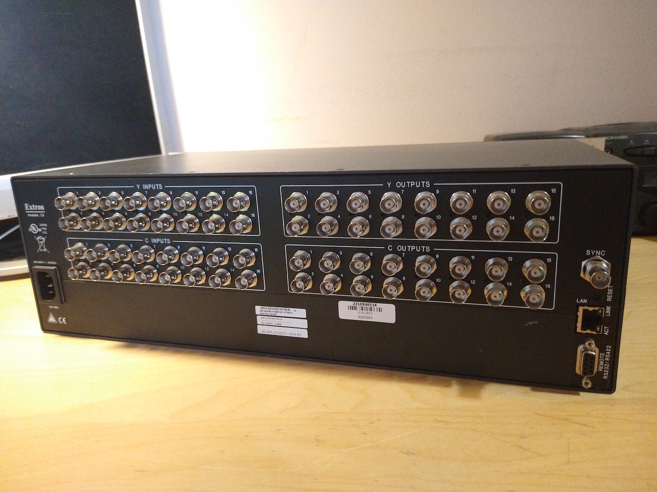 A rear view of the Extron maxtrix switcher. There are 64 BNC connections in total for video, divided between luma and chroma inputs and outputs. There is also a sync input, and DE-9 and RJ45 ports for remote control.